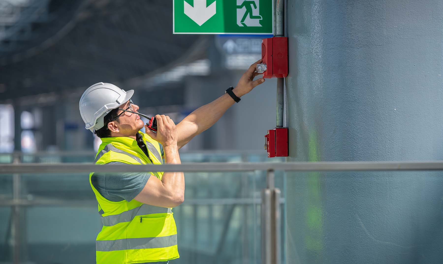 Engineer wearing safety uniform and helmet under checking fire alarm at a construction site 