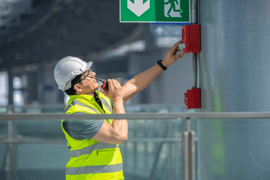 man on walkie talkie looking at emergency evacuation alarm